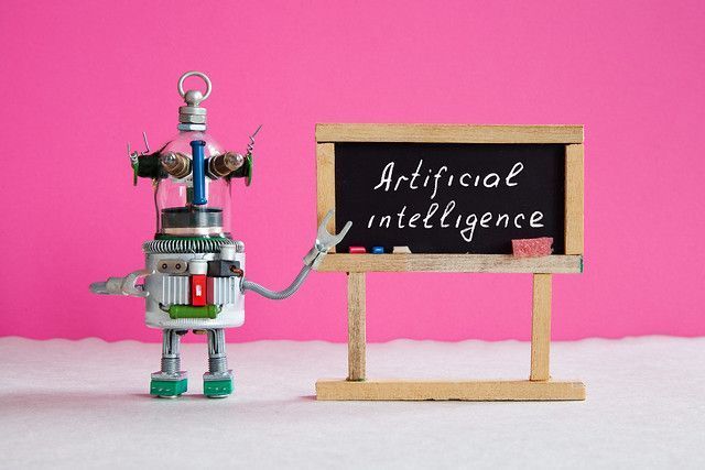 Robot pointing to artificial intelligence on a blackboard